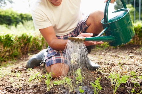 Community gardener working in a Carshalton garden bed with tools nearby.